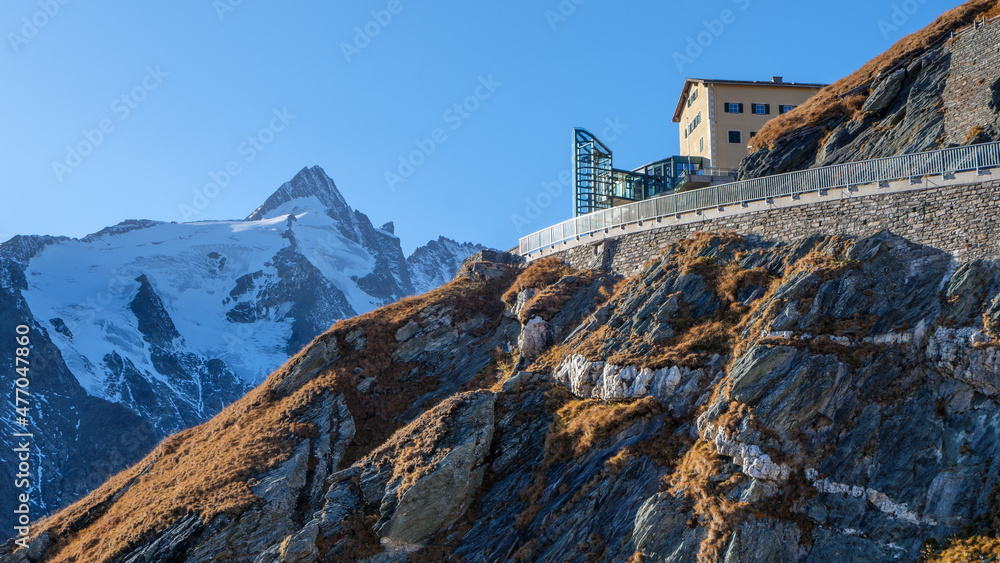 Αυτοκόλλητο Ridge with road, house and pegmatite veins in front of snowy peak