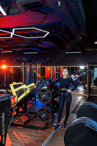 An experienced fitness trainer of a sporty woman stands in the gym and thinks about an exercise plan. Diet and weight loss concept. Personal trainers women in the gym