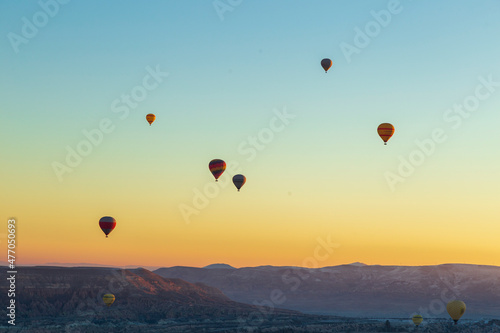 Hot air balloons flying over spectacular Cappadocia. Beautiful view of hot air balloons floating in sunrise blue sky over the mountain landscape of fairy chimneys