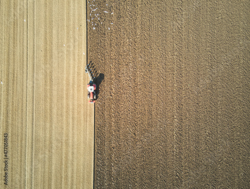 Overhead view of a lone tractor ploughing a sunny field in East Yorkshire, UK