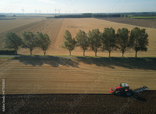 Overhead view of a lone tractor ploughing a sunny field in East Yorkshire, UK