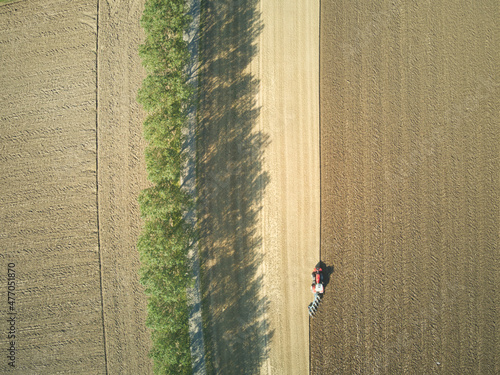 Overhead view of a lone tractor ploughing a sunny field in East Yorkshire, UK