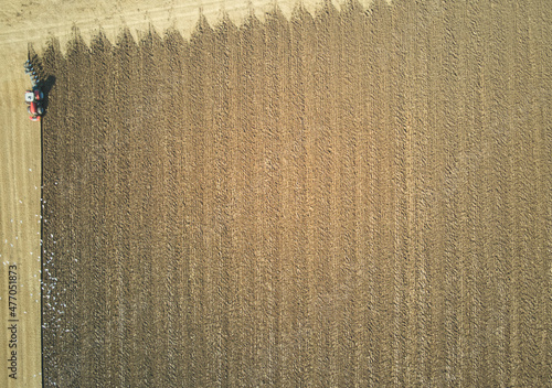 Overhead view of a lone tractor ploughing a sunny field in East Yorkshire, UK