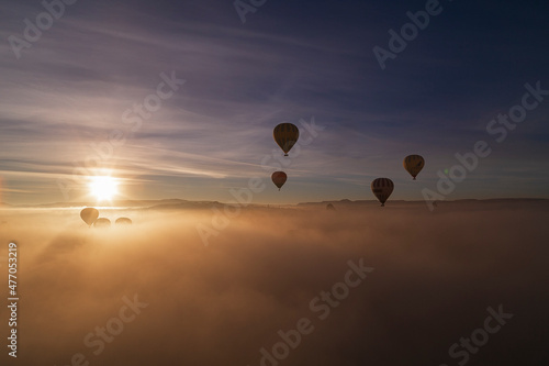 Hot air balloons flying over spectacular Cappadocia. Beautiful view of hot air balloons floating in sunrise blue sky over the mountain landscape of fairy chimneys