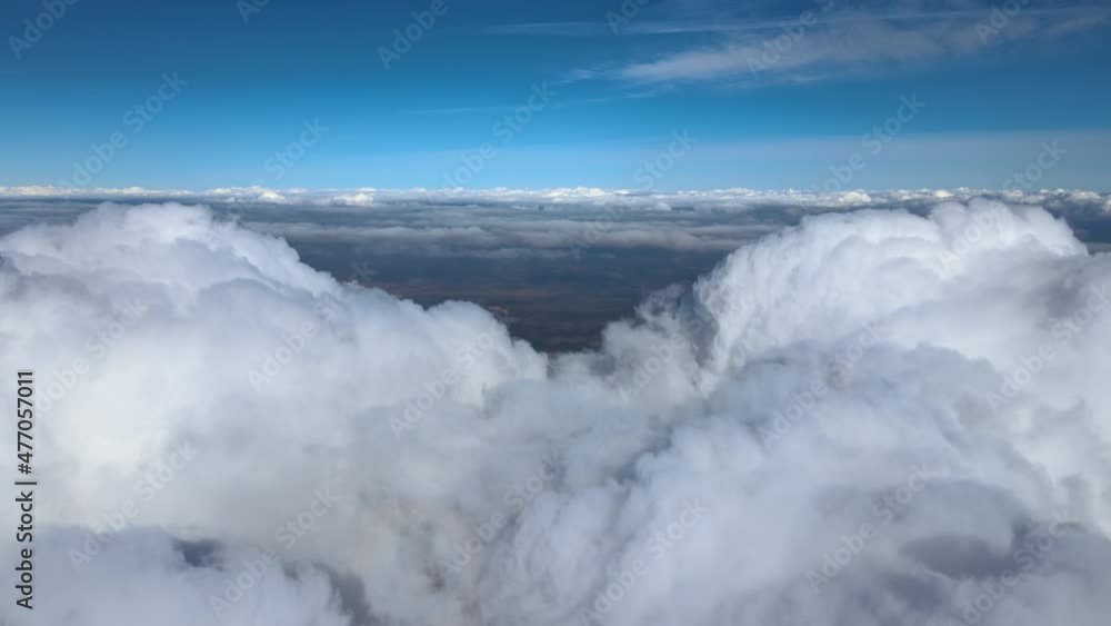 Aerial view from airplane window at high altitude of earth covered with white puffy cumulus clouds Aerial view from airplane window at high altitude of earth covered with white puffy cumulus clouds