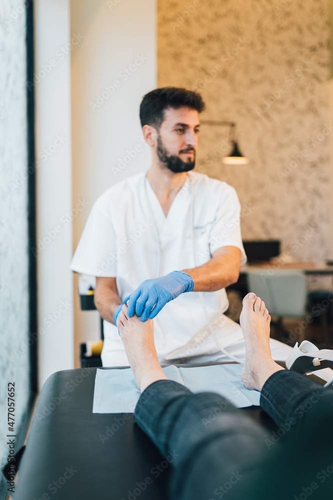 Chiropodist doing an ultrasound test to patient's foot. Chiropodist doing an ultrasound test to patient's foot.