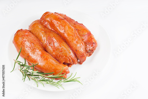 Fresh marinated chicken meat.Raw marinated chicken fillet in red sauce on a white plate on a light background with fresh rosemary leaves and spices.
