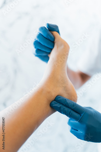 Close up of a podiatrist hands with medical gloves exploring the foot of a patient in the podiatry clinic.