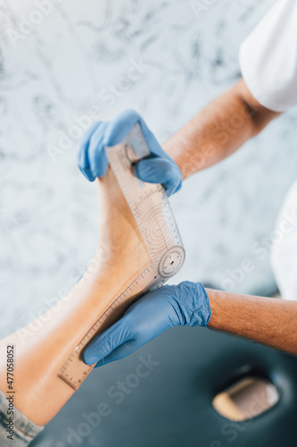 Close up of a podiatrist hands with medical gloves exploring the foot of a patient in the podiatry clinic.