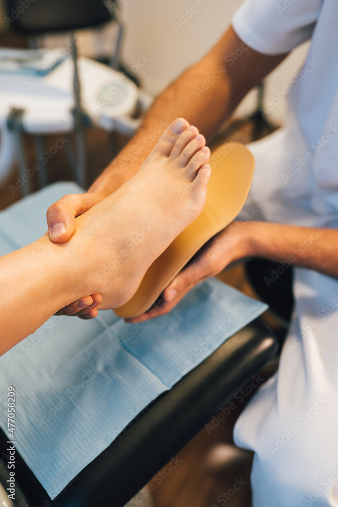 Chiropodist fitting an orthopedic foot insole to a patient. Chiropodist fitting an orthopedic foot insole to a patient.
