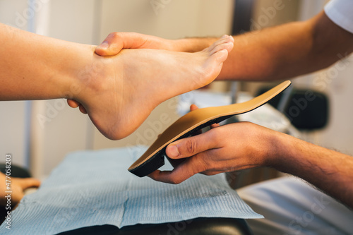 Chiropodist fitting an orthopedic foot insole to a patient.