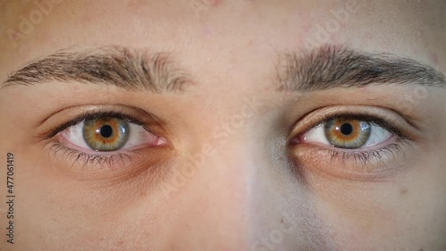 Macro close up of man's face opening beautiful blue and brown hazel eyes. Young Arab male model with natural central heterochromia and different eye colors waking up and looking at camera. 4K.