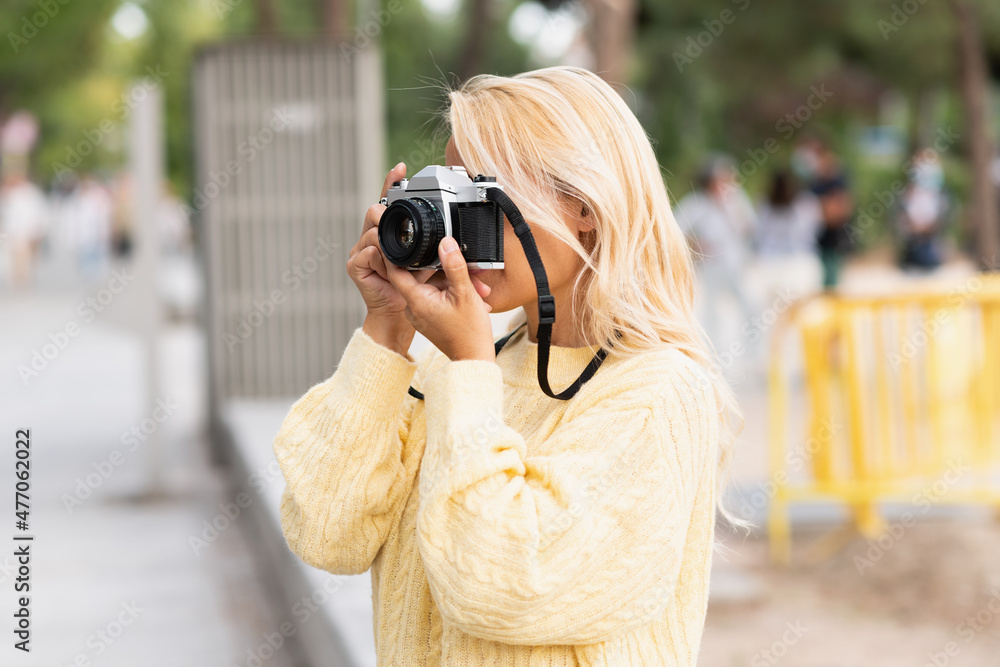 Woman taking a photo with a camera in the street