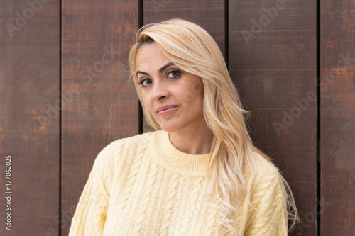 Beauty woman facing the camera while leaning on a wooden wall