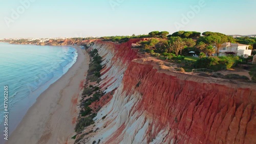 Landscape aerial view of Beach Falésia Açoteias or Praia da Falésia from above. Golden sunset over a Sandy rocky beach with high reds to whitish cliffs seen from above with turquoise ocean waves 4K. photo