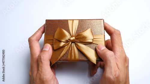Fototapeta Naklejka Na Ścianę i Meble -  A man's hand gives a gift box with a ribbon on a white background. Valentine concept, New year Concept, Christmas Concept. Top view, Anniversary Concept. High angle view, Flat Lay.