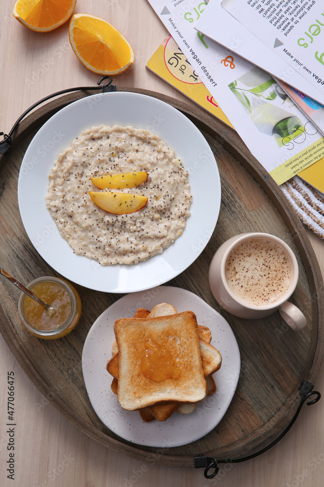 Wooden tray with delicious breakfast and magazines on table, flat lay Wooden tray with delicious breakfast and magazines on table, flat lay