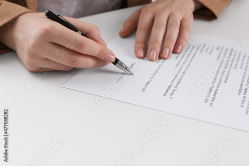 Businesswoman signing contract at white table, closeup of hands