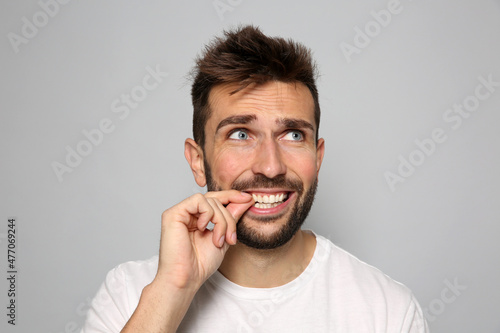 Man biting his nails on grey background