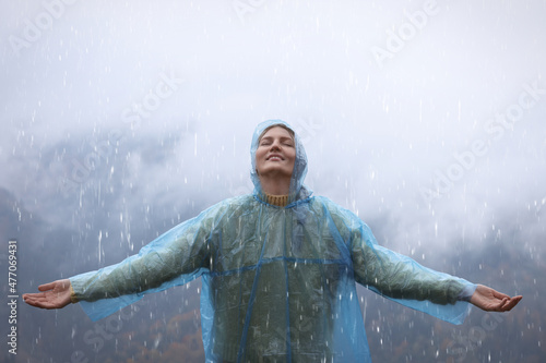 Young woman with raincoat enjoying rainy weather in mountains photo