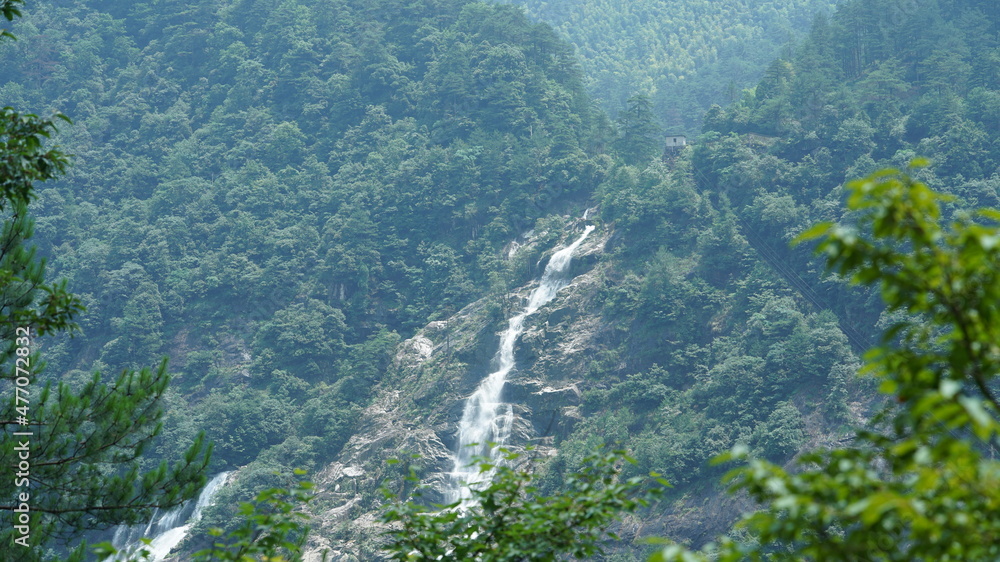 The beautiful countryside view with the waterfall flowing in the mountains after the rainy day