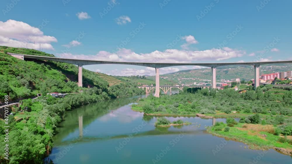 Scenic aerial view of Vila Real District along the Douro Valley River with bridges. Stunning massive Ponte Miguel Torga and Régua Pedestrian Bridge with the beautiful green town by the river in 4K. Scenic aerial view of Vila Real District along the Douro Valley River with bridges. Stunning massive Ponte Miguel Torga and Régua Pedestrian Bridge with the beautiful green town by the river in 4K.