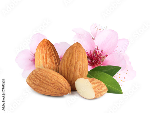 Tasty almonds, pink flowers and green leaves on white background