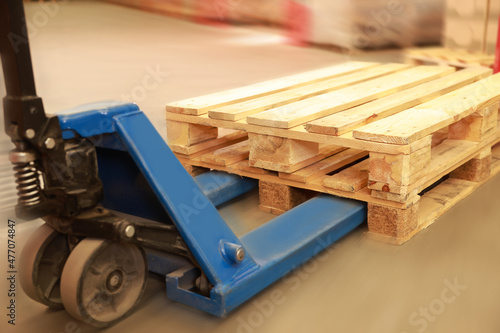 Modern manual forklift with wooden pallets in warehouse, closeup