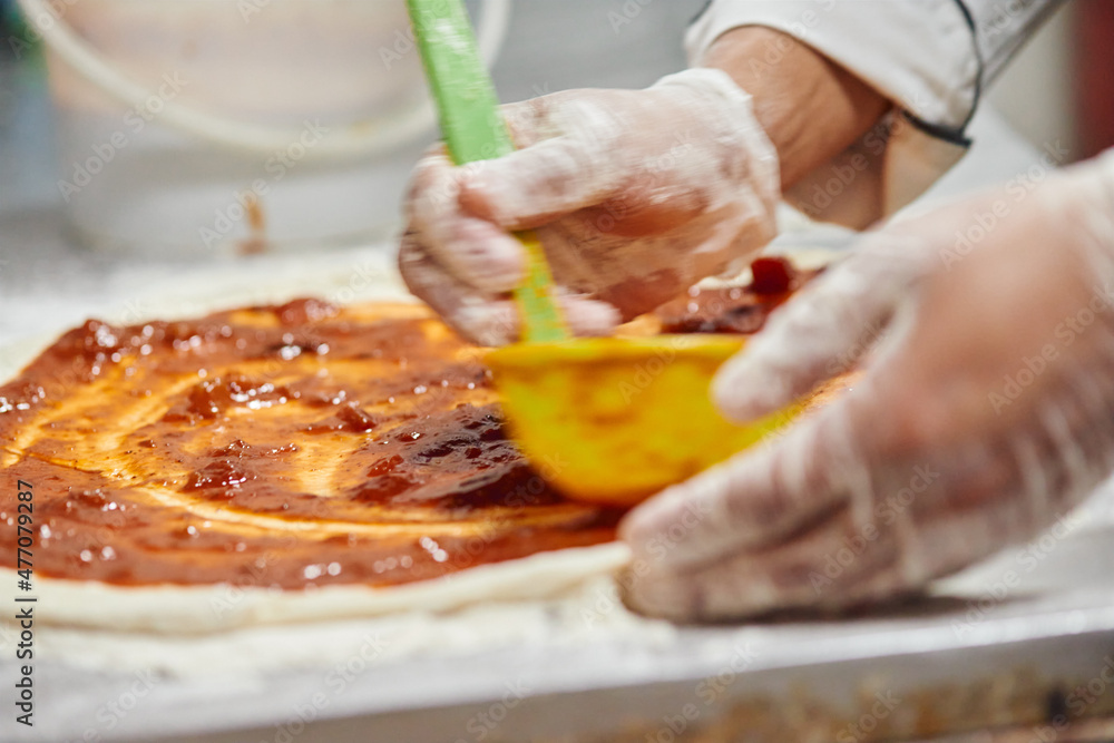 Sauce being poured on pizza dough