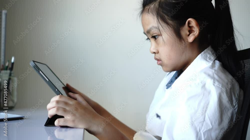 Little girl sitting studying on a tablet Little girl sitting studying on a tablet