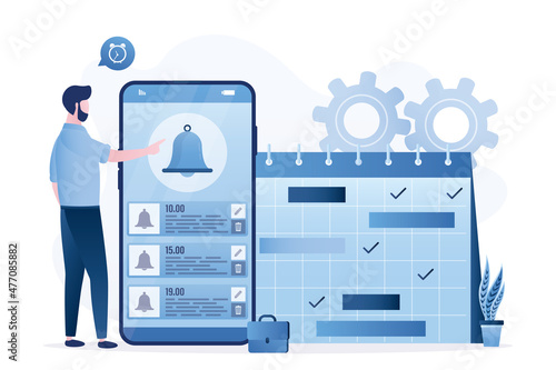 Businessman sets up notifications and an alarm clock on his smartphone. Paper calendar with notes. Alarm bell and time management app on mobile phone screen. Schedule of meetings and work.