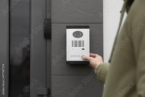 Obraz na płótnie Man ringing intercom with camera near building entrance, closeup