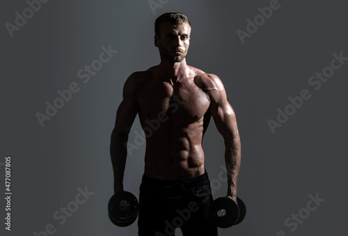 Sexy sporty torso, man with dumbbells. Portrait of athletic man with dumbbells. Shirtless man man with muscles torso in studio.