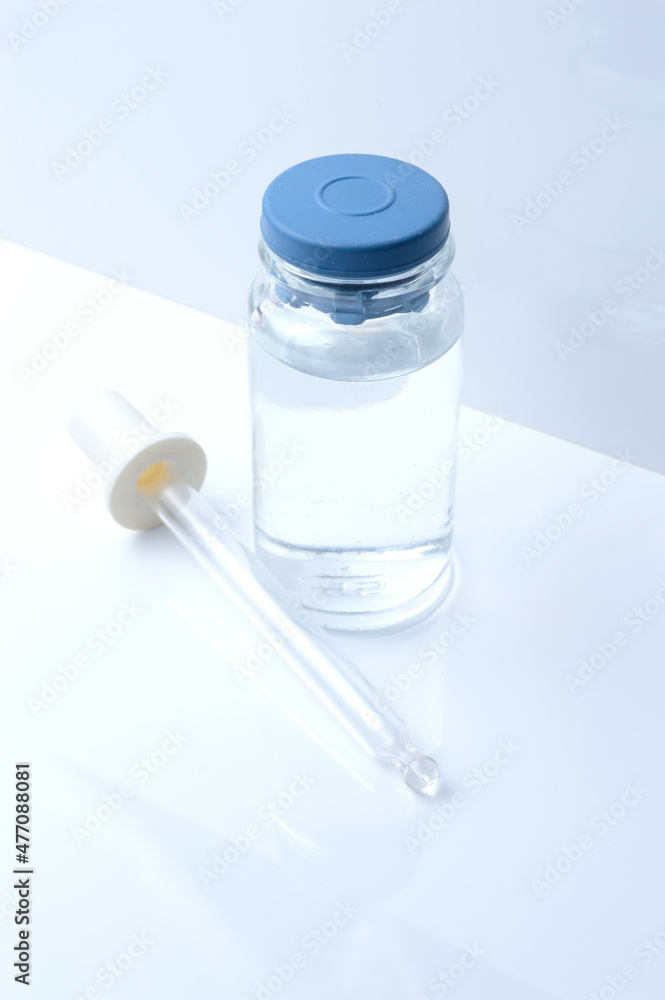 glass transparent jar and a cosmetic pipette with liquid droplets on a white background. glass transparent jar and a cosmetic pipette with liquid droplets on a white background.