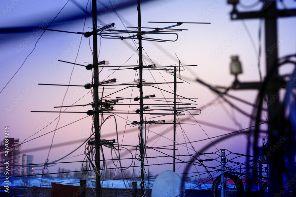 Television antennas and electric wires against the background of the evening sunset sky Television antennas and electric wires against the background of the evening sunset sky