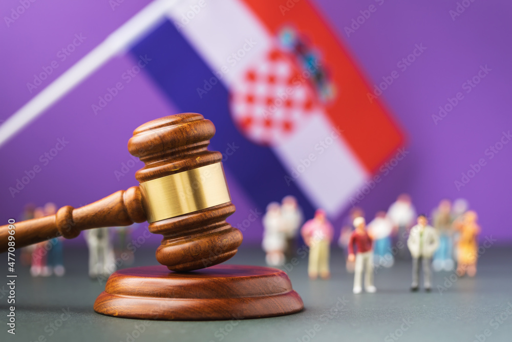 Judge gavel against the background of the blurred Croatian flag and plastic toy men, the concept of litigation in Croatian society