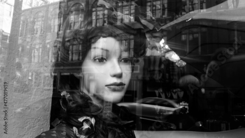 mannequin in window with reflection of buildings