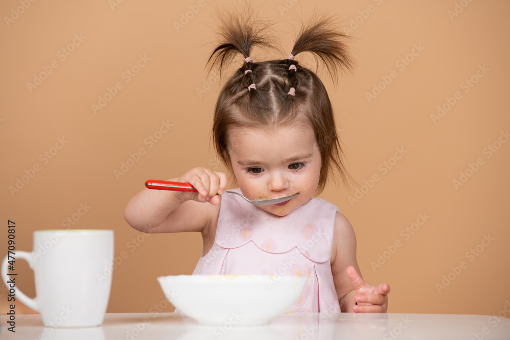 Portrait of cute Caucasian child kid with spoon. Hungry messy baby with plate after eating puree. Baby eating kids food. Portrait of cute Caucasian child kid with spoon. Hungry messy baby with plate after eating puree. Baby eating kids food.