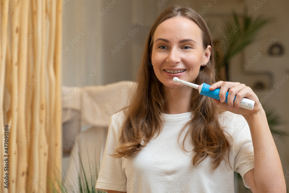 Mirror image of a beautiful young woman washing her teeth with a purple toothbrush in a bright bathroom. The concept of daily oral hygiene Mirror image of a beautiful young woman washing her teeth with a purple toothbrush in a bright bathroom. The concept of daily oral hygiene