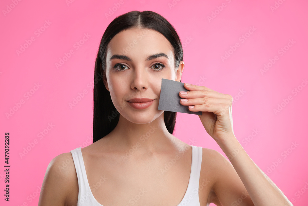 Beautiful woman using mattifying wipe on pink background Beautiful woman using mattifying wipe on pink background