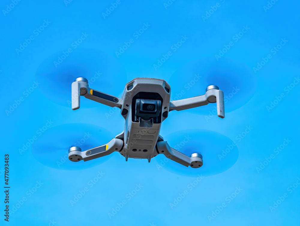 The flight of the drone against the blue sky. Drone in the air. Filming from the air. Take pictures in flight. Mini helicopter. Propeller blades. Ascend to the skies. Air space. Electronic technology.