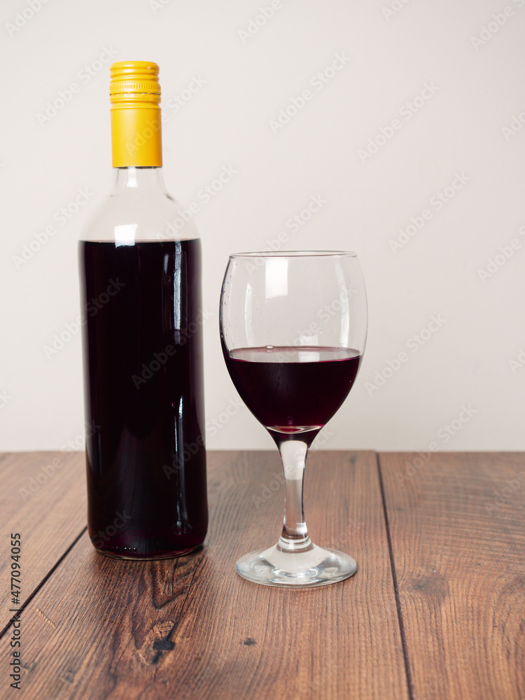 Still life scene. Bottle of red wine and one glass and wooden bowl with dark grapes. Bright color background. Food industry product. Still life scene. Bottle of red wine and one glass and wooden bowl with dark grapes. Bright color background. Food industry product.