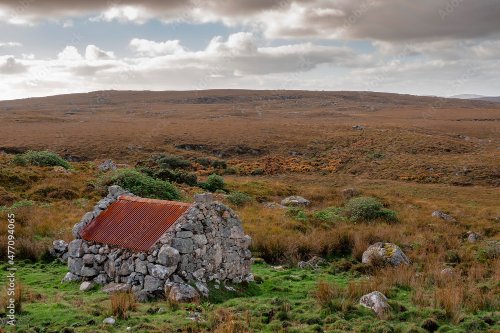 Small stone building with rusty red metal roof with beautiful nature scenery in the background. Connemara area, county Galway, Ireland. Storage hut in a field. Historical building. Cloudy sky Small stone building with rusty red metal roof with beautiful nature scenery in the background. Connemara area, county Galway, Ireland. Storage hut in a field. Historical building. Cloudy sky