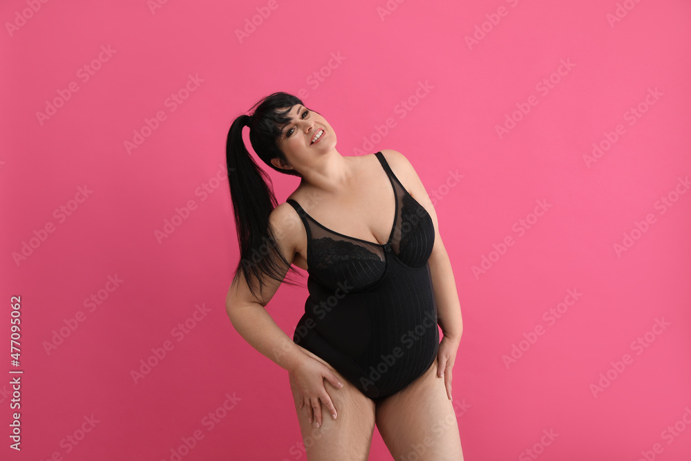 Obraz premium Beautiful overweight woman in black underwear on pink background. Plus-size model