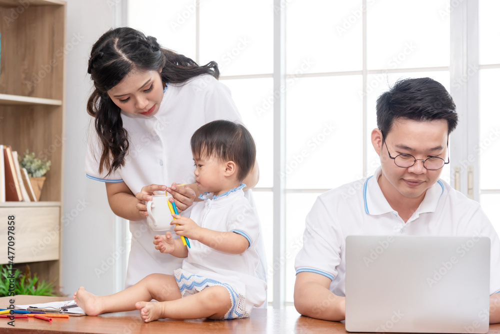 Asian mother taking care of baby while father working on computer, work from home family. Asian mother taking care of baby while father working on computer, work from home family.