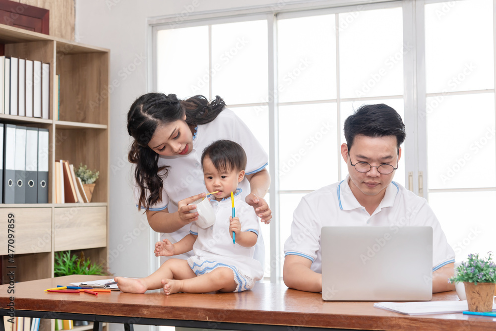 Asian mother taking care of baby while father working on computer, work from home family. Asian mother taking care of baby while father working on computer, work from home family.