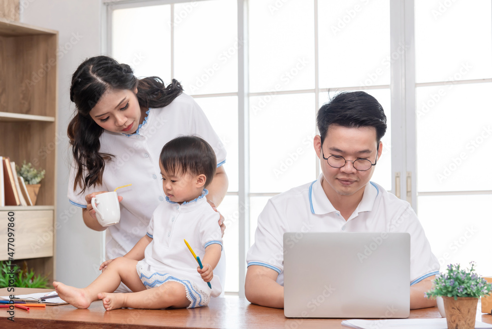 Asian mother taking care of baby while father working on computer, work from home family. Asian mother taking care of baby while father working on computer, work from home family.
