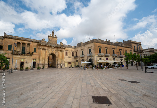 Lecce, Puglia, Italy. August 2021. Amazing view walking towards one of the access gates to the historic center. People come out of the old town through it. Beautiful summer day.