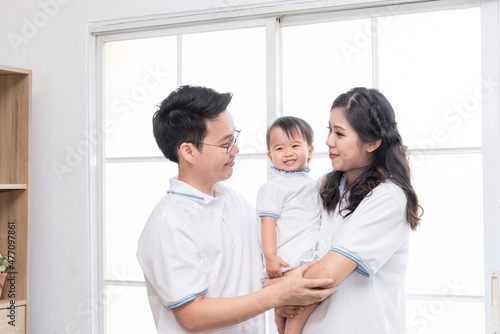 Asian happy family, father and mother kissing their baby at home. © rachaphak
