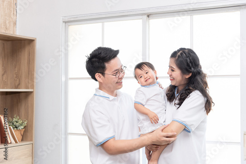 Asian happy family, father and mother kissing their baby at home.